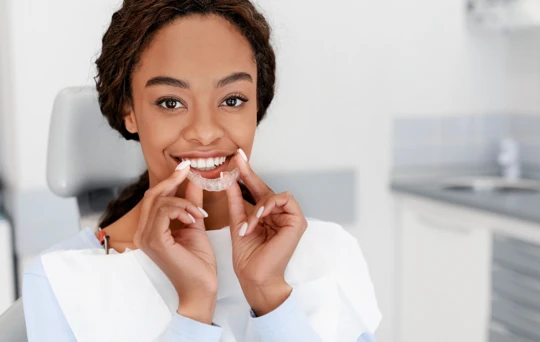 Women sitting in Maven Dental chair holding Invisalign clear aligner 