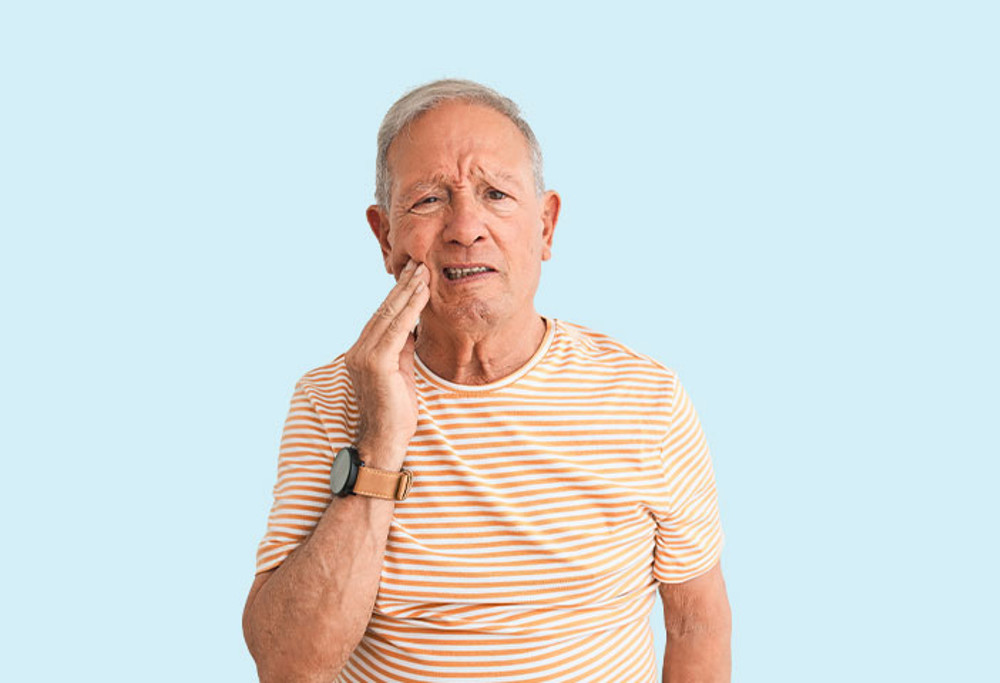Mature age man in striped shirt touching sore tooth