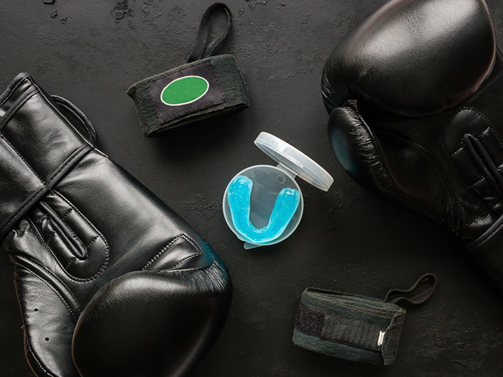Blue mouthguard in between black boxing gloves 