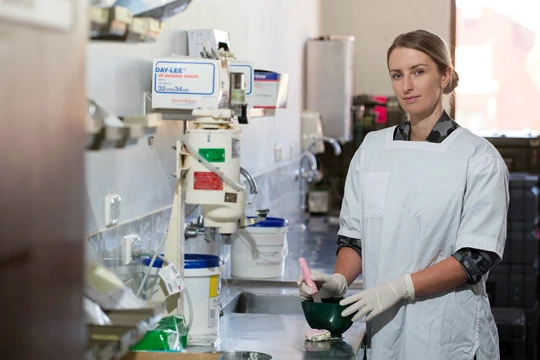 Woman wearing coat over Australian Army uniform standing in dental lab