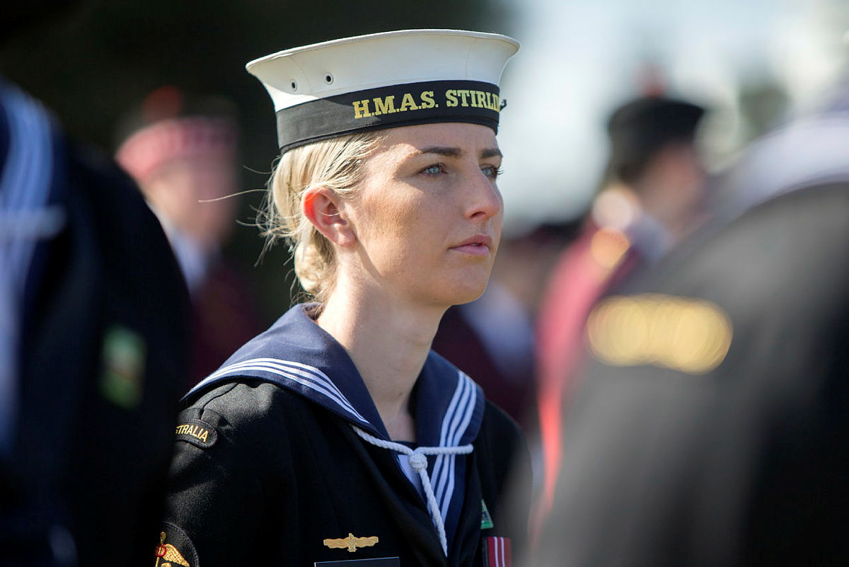 Woman standing amongst crowd wearing Australian Navy uniform 
