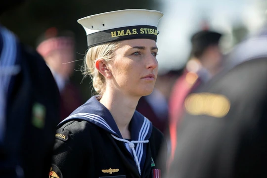 Woman standing amongst crowd wearing Australian Navy uniform 