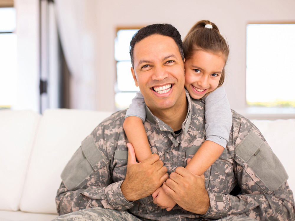 Man dressed in army uniform cuddling daughter  