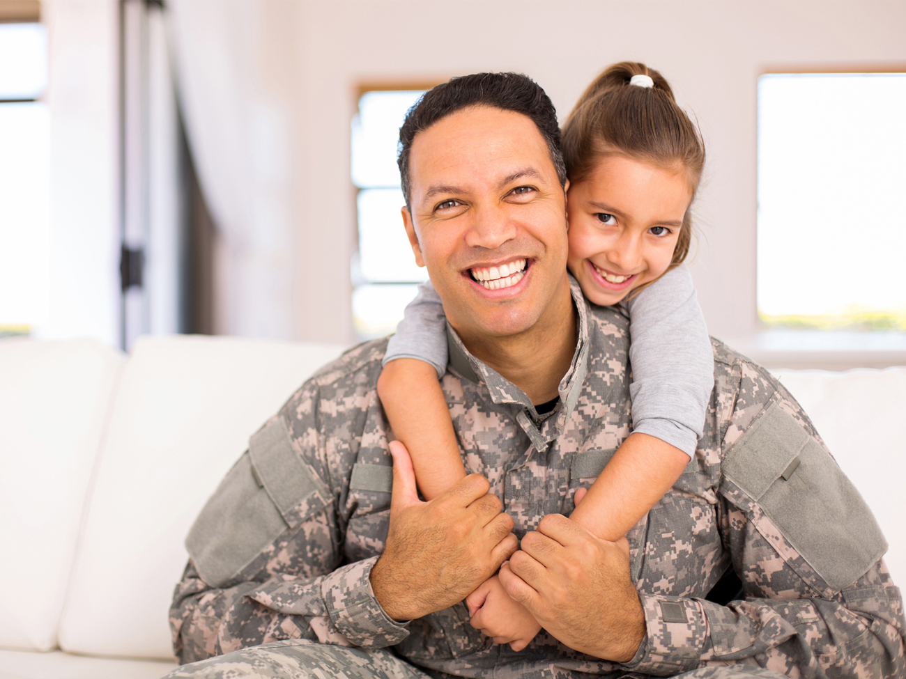 Male dressed in army uniform cuddling daughter 
