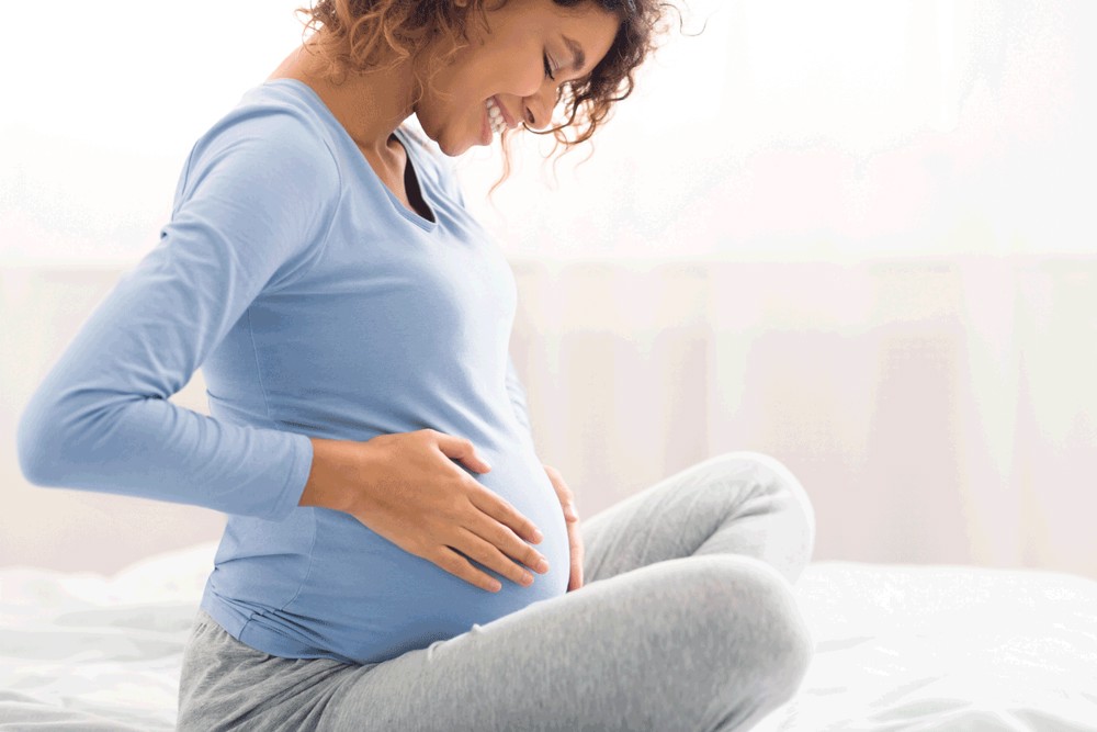 Pregnant Woman smiling at baby bump 
