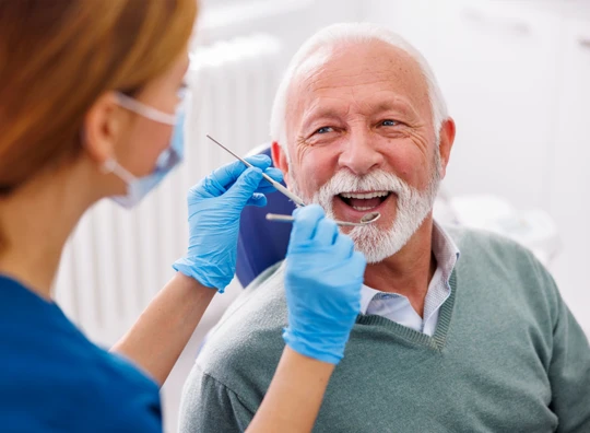 Mature aged man sitting in dental chair or oral cancer screening 